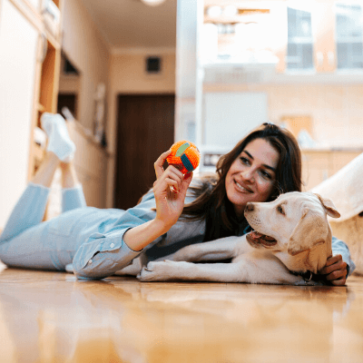 dog and owner on the floor playing with a ball