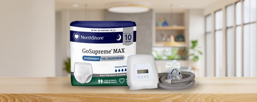NorthShore GoSupreme MAX Overnight Underwear package displayed beside a CPAP machine, mask, and hose on a bedside table.