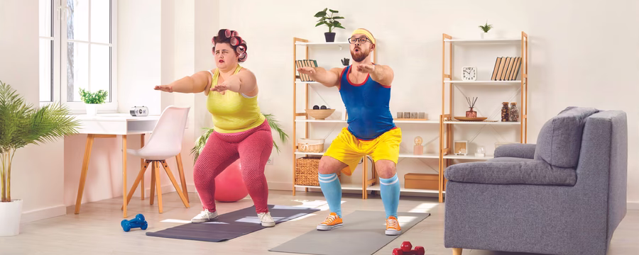 Two adults exercise at home on yoga mats, performing squats beside exercise balls. The woman wears a neon yellow top and pink leggings, while the man wears a blue tank top, yellow shorts, and blue knee-high socks. Dumbbells are on the floor, with shelves and plants in the background.