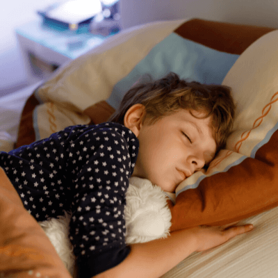 male child sleeping in bed with teddy bear