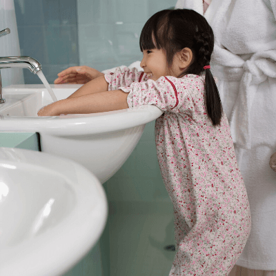 female toddler washing hands with parent in bathroom