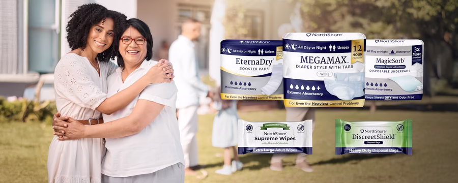 Two smiling women embracing outdoors, with NorthShore incontinence care products displayed, highlighting essential supplies for caregivers.