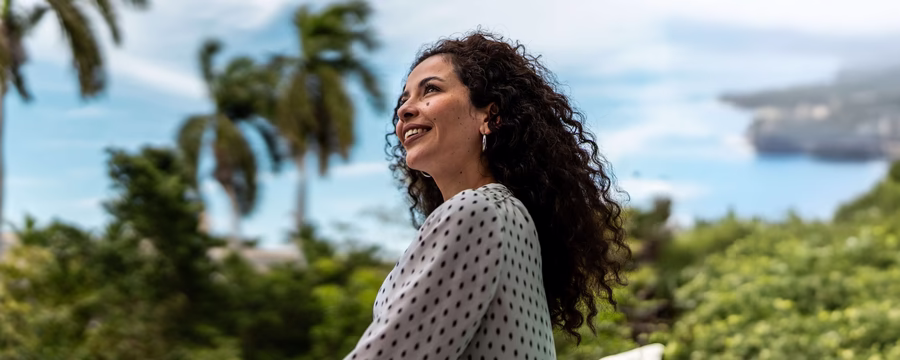 Confident woman smiling outdoors, enjoying a tropical view while embracing leak-free living with NorthShore protection.