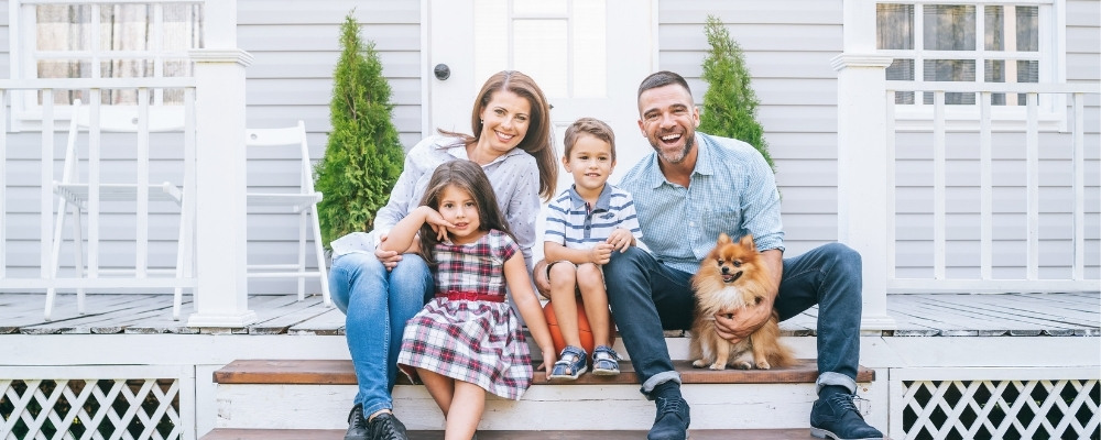 Happy family sitting in front of home