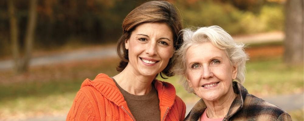mother and adult daughter posing outdoors