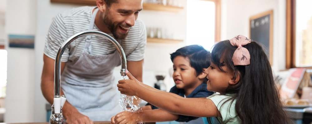 Man showing children how to wash hands