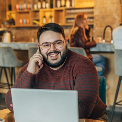 man on laptop while talking on the phone