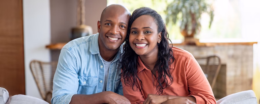 Happy couple sitting together and smiling at home, reflecting connection and joy in relationships.