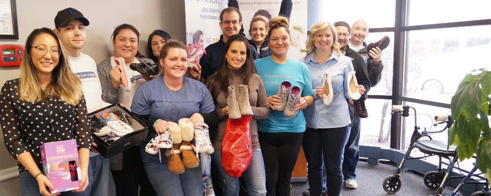 Group of NorthShore staff in front office holding shoes for donation